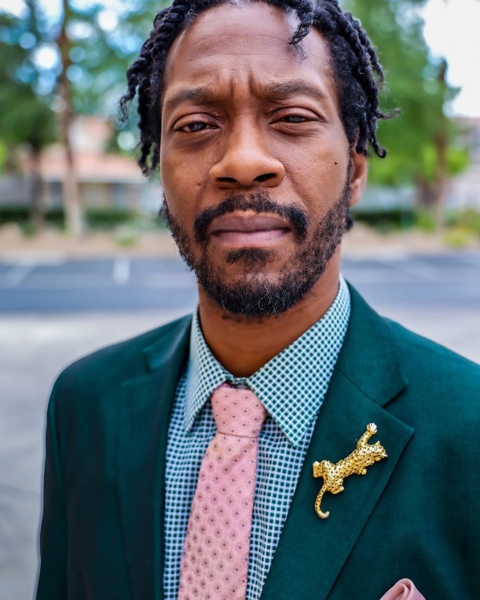 Emerald suit with a pink knit tie and a gold leopard lapel pin
