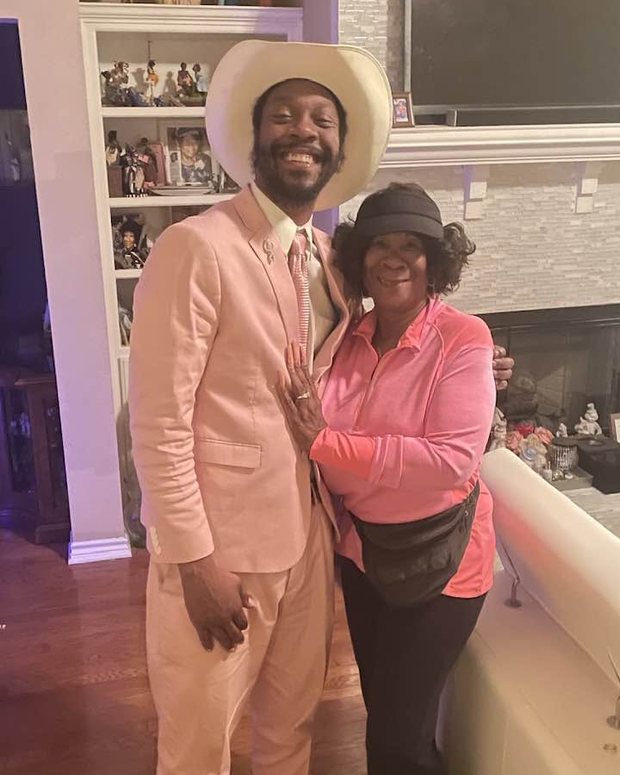 George Gentleman in a blush suit and a white hat, standing with his mother in pink